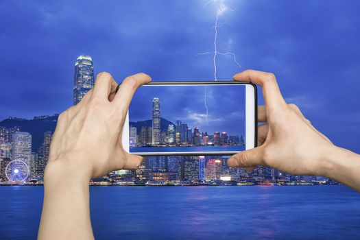 Girl taking pictures on mobile smart phone in Thunderstorm HongKong cityscape at night , Hong kong city.