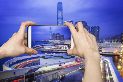 Girl taking pictures on mobile smart phone in Night view traffic in Hong Kong at sunset time