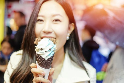 Chinese Asian young female model eating ice cream cone on Hong Kong Street