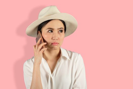 young attractive asian woman waiting answer for a smart phone on Pink backgroud 