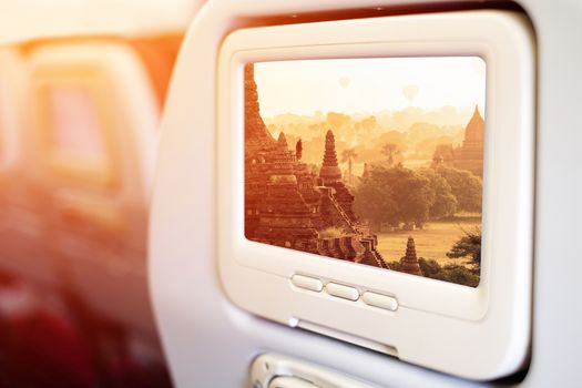 Aircraft monitor in front of passenger seat showing Bagan temples sunrise, Myanmar