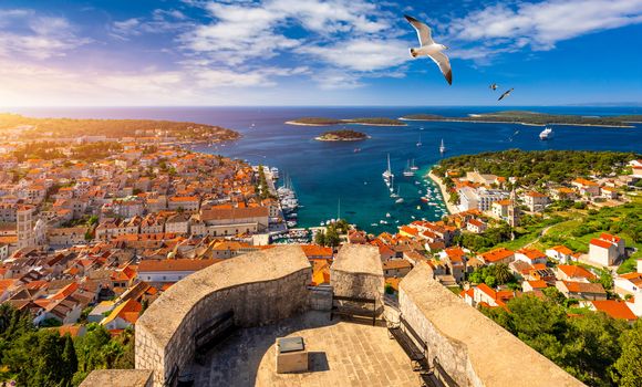 Hvar town with seagull's flying over city, famous luxury travel destination in Croatia. Boats on Hvar island, one of the many Islands near Dubrovnik and Korcula on the Dalmatian Coast of Croatia.