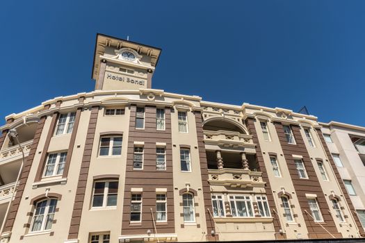 Sydney, Australia - February 11, 2019: Yellow and brown Bondi Hotel facade and clock tower under blue sky in Bondi Beach.