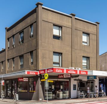 Sydney, Australia - February 11, 2019: Nails and waxing salon on corner of Gould and Curlewes street in Bondi Beach. White on red advertisements, display windows in brown triple story building.