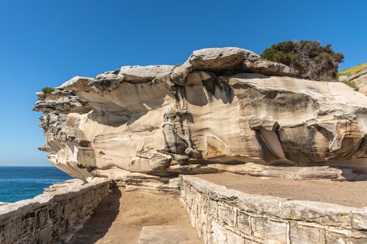 Sydney, Australia - February 11, 2019: Mackenzies Point beige rock formation on South shore lands end of Bondi beach. Blue water and blue sky.