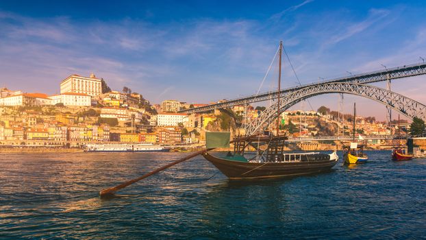 Port wine boats at the waterfront with Dom Luis bridge and the old town on the Douro River in Ribeira in the city centre of Porto in Porugal in Europe. Portugal, Porto