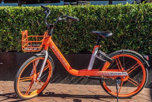 Sydney, Australia - February 11, 2019: Closeup of parked orange MOBIKE bicycle for rent as seen in First Fleet Park near Circular Bay.