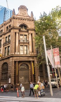 Sydney, Australia - February 12, 2019: Corner entrance to historic Austalasain Bank Building on George Street and Martin Place. People on street, green foliage and Year of the Pig banner.