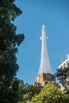 Sydney, Australia - February 12, 2019: White replica of Eifel Tower on top of AWA building just off Wynyard Park against blue sky. Green foliage frame.