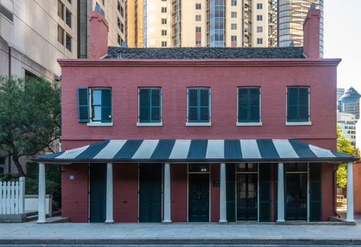Sydney, Australia - February 12, 2019: Closeup of Maroon painted historic house in Cumberland Street in The Rocks neighborhood lost in middle of tall sky scraper buildings.
