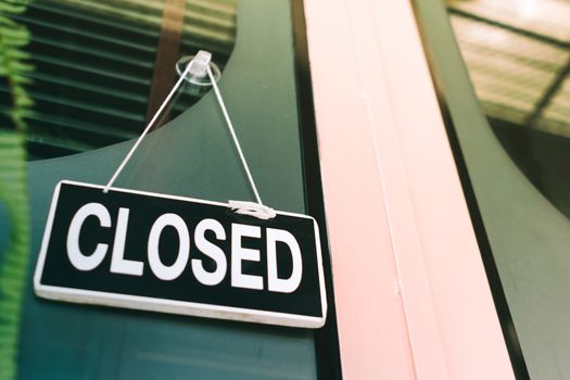 A Sign board of sorry we are closed hang on door of business shop with nature green background