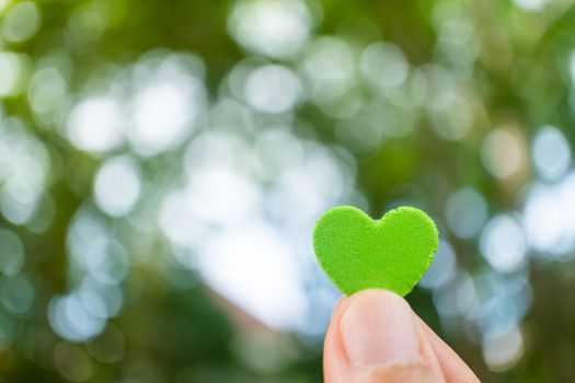 Hand hold little heart meaning feel love with green nature bokeh background.