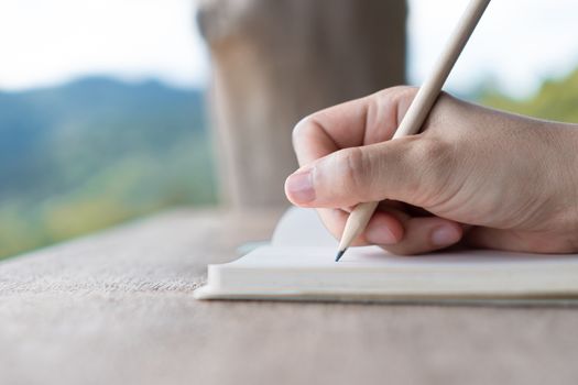 Woman hand writing down in small white memo notebook for take a note not to forget or to do list plan for future.