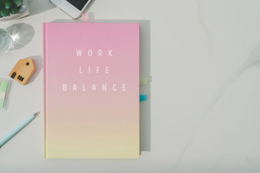 Colorful pastel white notebook for journal or diary on marble texture table.Work life balance quote phrase on book cover.