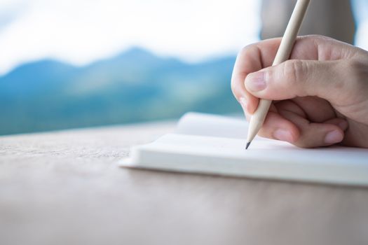 Woman hand writing down in small white memo notebook for take a note not to forget or to do list plan for future.