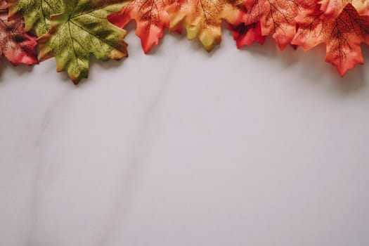 Top view of autumn maple leaf on white marble texture abstract background with copy space.