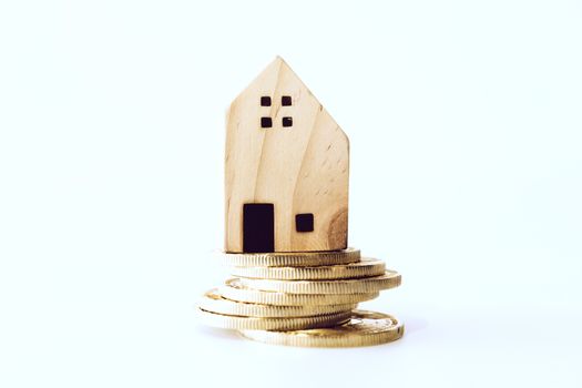 Mini house model on gold coin with clean white copyspace background. Business invest property saving concept.