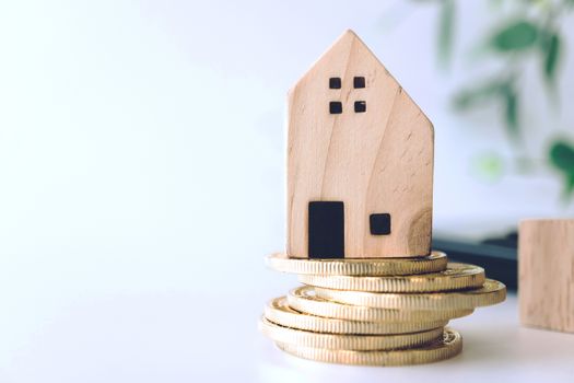 Mini house model on gold coin with clean white copyspace background. Business invest property saving concept.