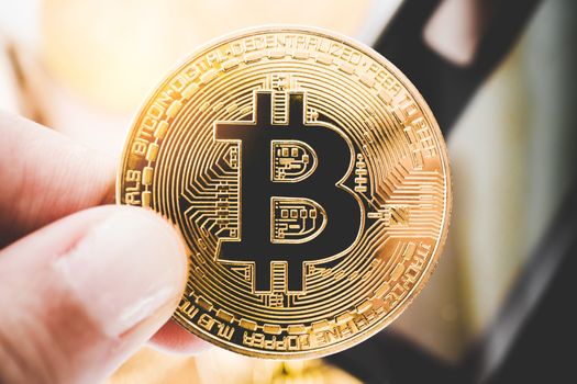 Hand hold a symbol of Bitcoins as digital money cryptocurrency background.