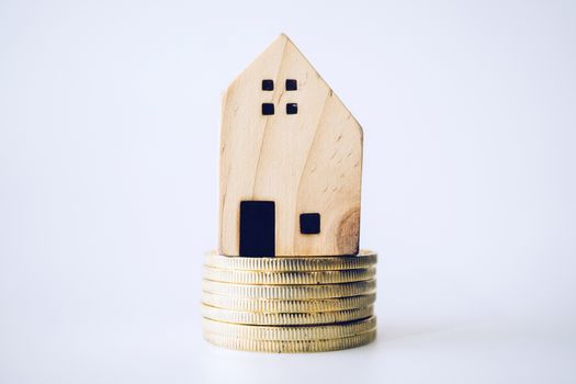 Mini house model on gold coin with clean white copyspace background. Business invest property saving concept.