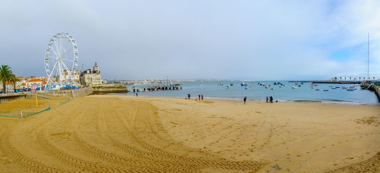 CASCAIS, PORTUGAL - DECEMBER 28, 2017: Panoramic view of the Ribeira Beach, the Seixas Palace and the Ferris Wheel, with visitors, in Cascais, Portugal