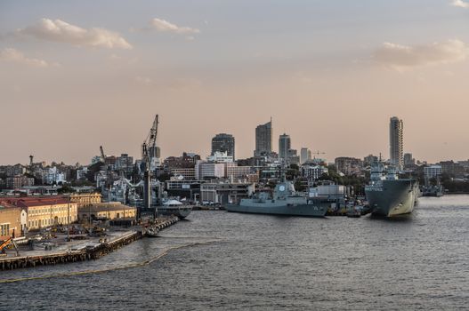 Sydney, Australia - February 12, 2019: Several large Navy ships at Royal Australian Navy Heritage Centre with housing in back under an evening twilight sky.