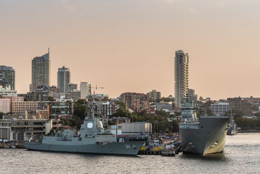 Sydney, Australia - February 12, 2019: Several large Navy ships at Royal Australian Navy Heritage Centre with housing in back under an evening twilight sky.