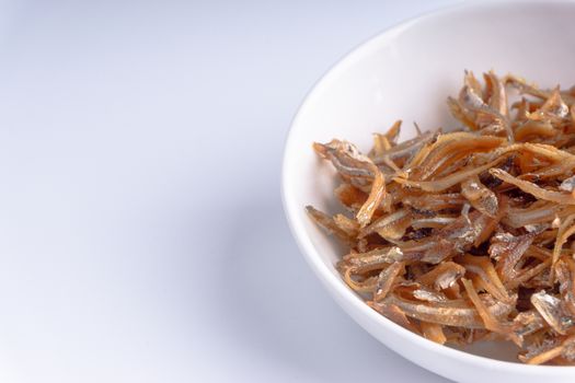 Fried anchovies in bowl close up with selective focus and crop fragment