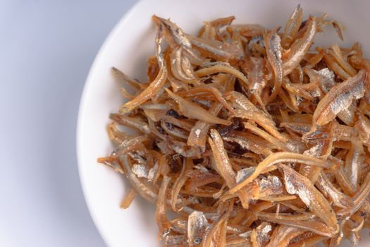 Fried anchovies in bowl close up with selective focus and crop fragment