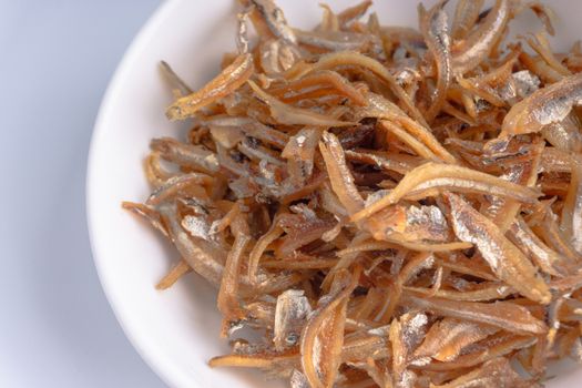 Fried anchovies in bowl close up with selective focus and crop fragment