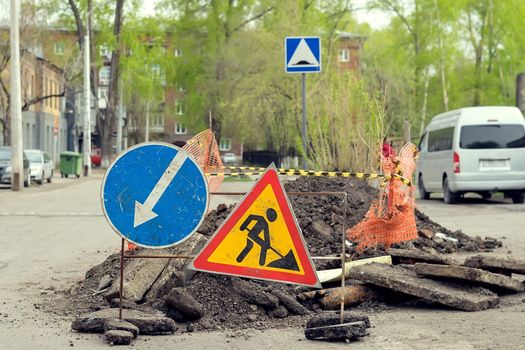 road sign, detour, road repair on the background of the road and broken asphalt covering on the urban street