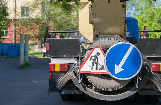 a road service repair truck stands on the street with signs indicating that repairs are being carried out