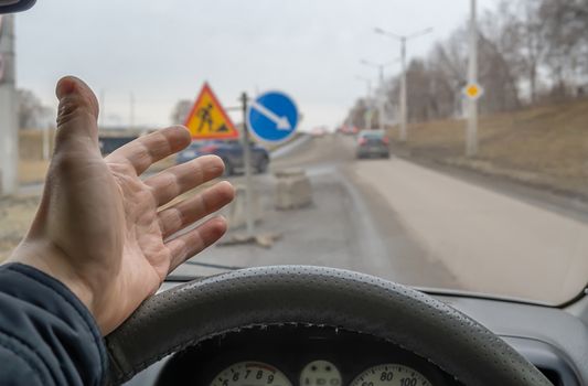 hand, the palm of a driver behind the wheel of a car who is outraged by road repairs and road signs installed