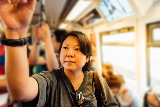 Asian woman travel on skytrain train in city. Many people in city used skytrain to save time.