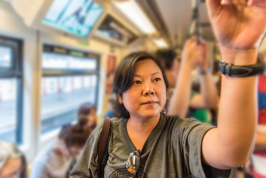 Asian woman travel on skytrain train in city. Many people in city used skytrain to save time.