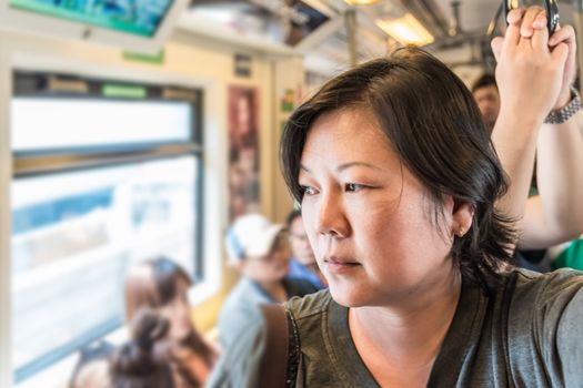 Asian woman travel on skytrain train in city. Many people in city used skytrain to save time.