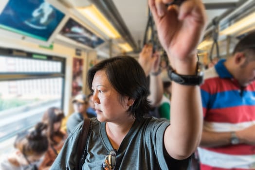 Asian woman travel on skytrain train in city. Many people in city used skytrain to save time.