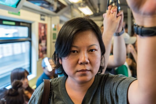 Asian woman travel on skytrain train in city. Many people in city used skytrain to save time.