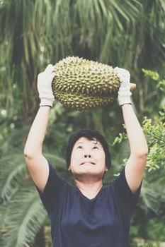 Asian woman farmer holding Durian is a king of fruit in Thailand and asia fruit have a spikes shell and sweet can buy at Thai street food and fruit market at agriculture farm