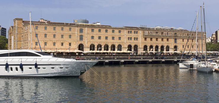 BARCELONA, SPAIN - JULY 4, 2015: The building "Palau de Mar" (1880-1890) home of museum "Museu d'Historia de Catalunya" in front of the harbor.

Barcelona, Spain - July 4, 2015: The building "Palau de Mar" (1880-1890) home of museum "Museu d'Historia de Catalunya" in front of the harbor. People walking at the promenade.