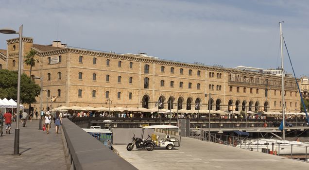 BARCELONA, SPAIN - JULY 4, 2015: The building "Palau de Mar" (1880-1890) home of museum "Museu d'Historia de Catalunya" in front of the harbor.

Barcelona, Spain - July 4, 2015: The building "Palau de Mar" (1880-1890) home of museum "Museu d'Historia de Catalunya" in front of the harbor. People walking at the promenade.