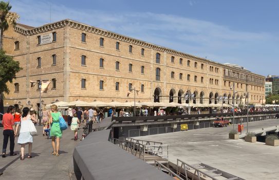 BARCELONA, SPAIN - JULY 4, 2015: The building "Palau de Mar" (1880-1890) home of museum "Museu d'Historia de Catalunya" in front of the harbor.

Barcelona, Spain - July 4, 2015: The building "Palau de Mar" (1880-1890) home of museum "Museu d'Historia de Catalunya" in front of the harbor. People walking at the promenade.