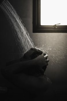 Asian man 40s showering in bathroom for clean a body and relax by bare and water drops from shower to the head and all body