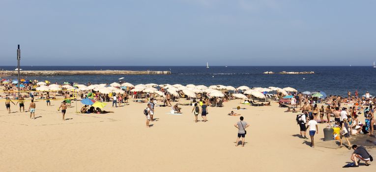BARCELONA, SPAIN - JULY 4, 2015: A crowd of bathers in La Barceloneta Beach in Barcelona, Spain. This popular beach hosts about 500,000 visitors from everywhere during the summer season.

Barcelona, Spain - July 4, 2015: A crowd of bathers in La Barceloneta Beach in Barcelona, Spain. This popular beach hosts about 500,000 visitors from everywhere during the summer season.