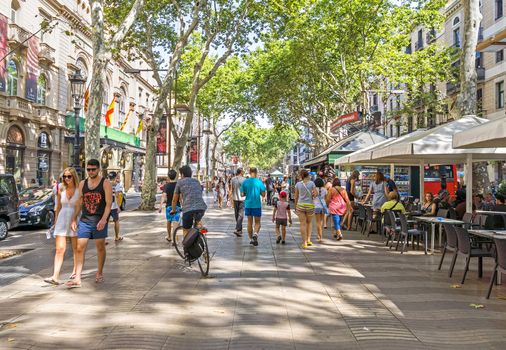 BARCELONA, SPAIN - JULY 6, 2015: Hundreds of people promenading in the busiest street of Barcelona, the Ramblas. The street extends 1.2 kilometers connects the Placa de Catalunya in the centre with the Christopher Columbus Monument at Port Vell.

Barcelona, Spain - July 6, 2015: Hundreds of people promenading in the busiest street of Barcelona, the Ramblas. The street extends 1.2 kilometers connects the Placa de Catalunya in the centre with the Christopher Columbus Monument at Port Vell.