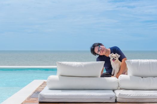 Asian woman and dog happy smile hugging on white beach bed at outdoor swimming pool seaside turquoise sea or ocean with horizon of blue sky at resort or hotel when vacation travel for relax