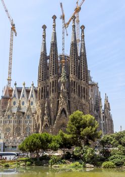 BARCELONA, SPAIN - JULY 6, 2015: La Sagrada Familia - the impressive cathedral designed by Gaudi, which is being build since 19 March 1882 and is not finished yet.

Barcelona, Spain - July 6, 2015: La Sagrada Familia - the impressive cathedral designed by Gaudi, which is being build since 19 March 1882 and is not finished yet. People are walking by street.