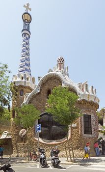 BARCELONA, SPAIN - JULY 6, 2015: Architecture of Park Guell by architect Antonio Gaudi.

Barcelona, Spain - July 6, 2015: Architecture of Park Guell by architect Antonio Gaudi. People are walking by street.