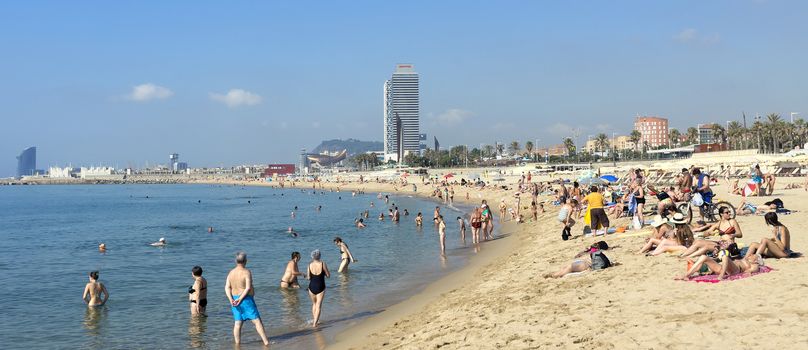 BARCELONA, SPAIN - JULY 13, 2015: Barceloneta Beach and skyscraper Torre Mapfre in the Olympic Port. It is named after its owner, Mapfre, an insurance company.

Barcelona, Spain - July 13, 2015: Barceloneta Beach and skyscraper Torre Mapfre in the Olympic Port. It is named after its owner, Mapfre, an insurance company. This tower holds the title for highest helipad in Spain at 505 feet above ground. People are resting on the beach.