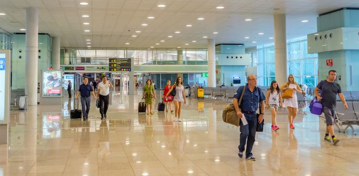 BARCELONA, SPAIN - JULY 16, 2015: The public area at the Terminal T1 of El Prat-Barcelona airport.

Barcelona, Spain - July 16, 2015: The public area at the Terminal T1 of El Prat-Barcelona airport. This airport was inaugurated in 1963. Airport is one of the biggest in Europe and one of the busiest in the world. People are walking.